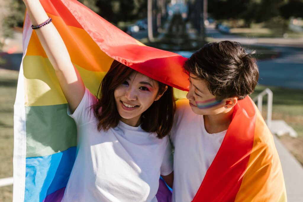 Happy couple embracing Pride with a colorful rainbow flag outdoors.